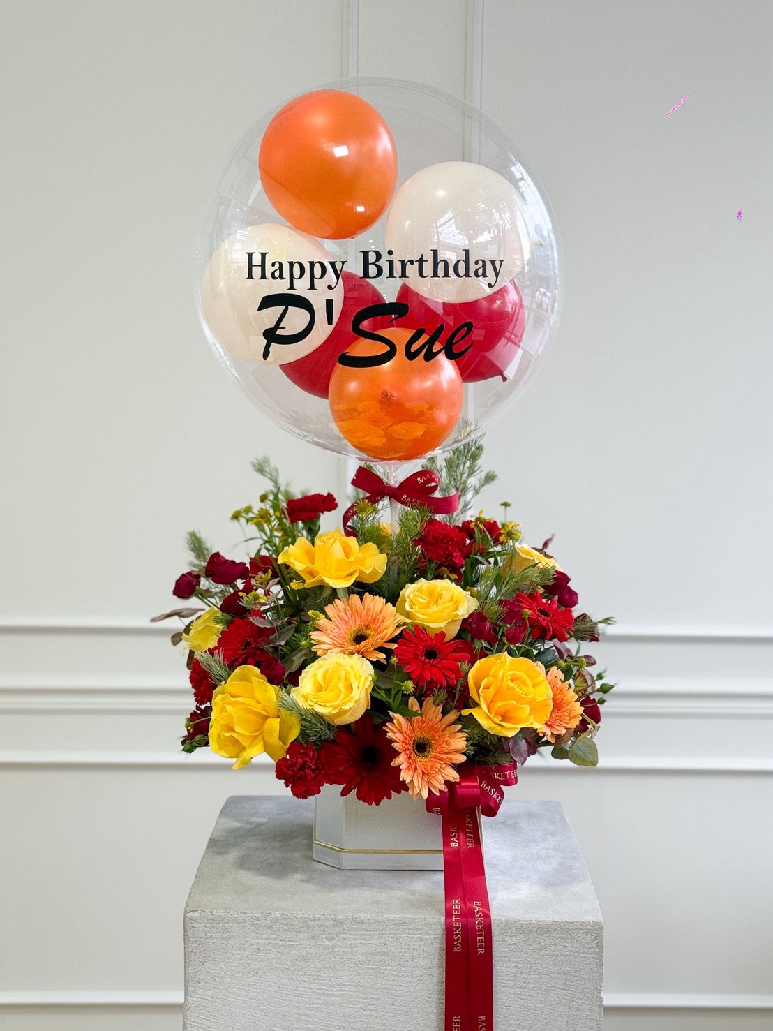 An elegant birthday bouquet of red, yellow, and orange flowers with a festive balloon and ribbon, delivered in Bangkok.