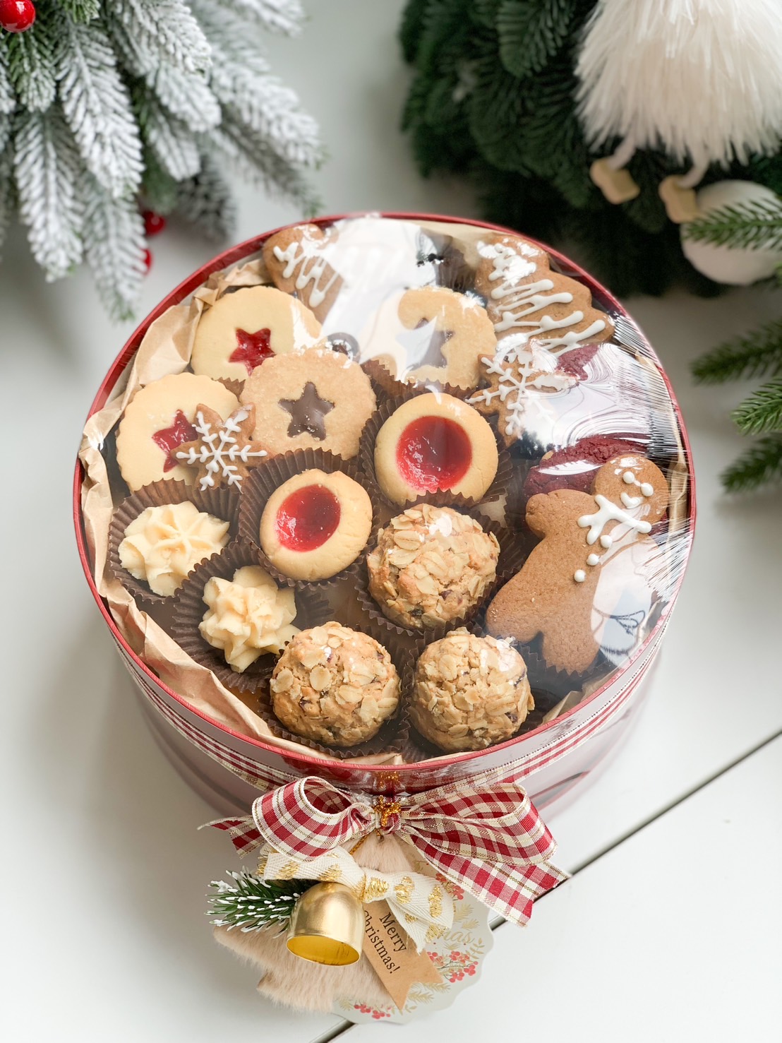 Two festive gift boxes, one green and one red, filled with assorted holiday cookies, including gingerbread men, shortbread, and jam-filled biscuits.