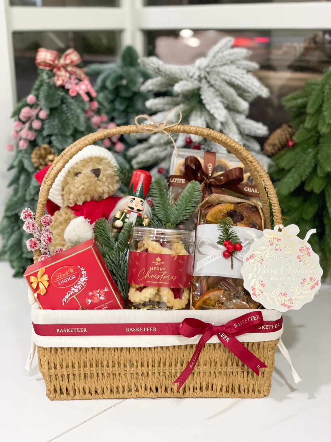 Holiday gift basket with teddy bear, fruitcake, cookies, and festive treats, perfect for Christmas celebrations.