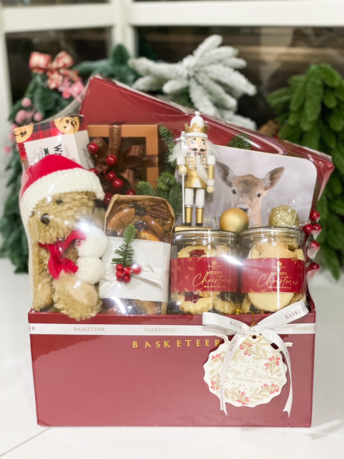 Holiday gift box with teddy bear, cookies, fruitcake, and festive treats, beautifully packaged for Christmas gifting.