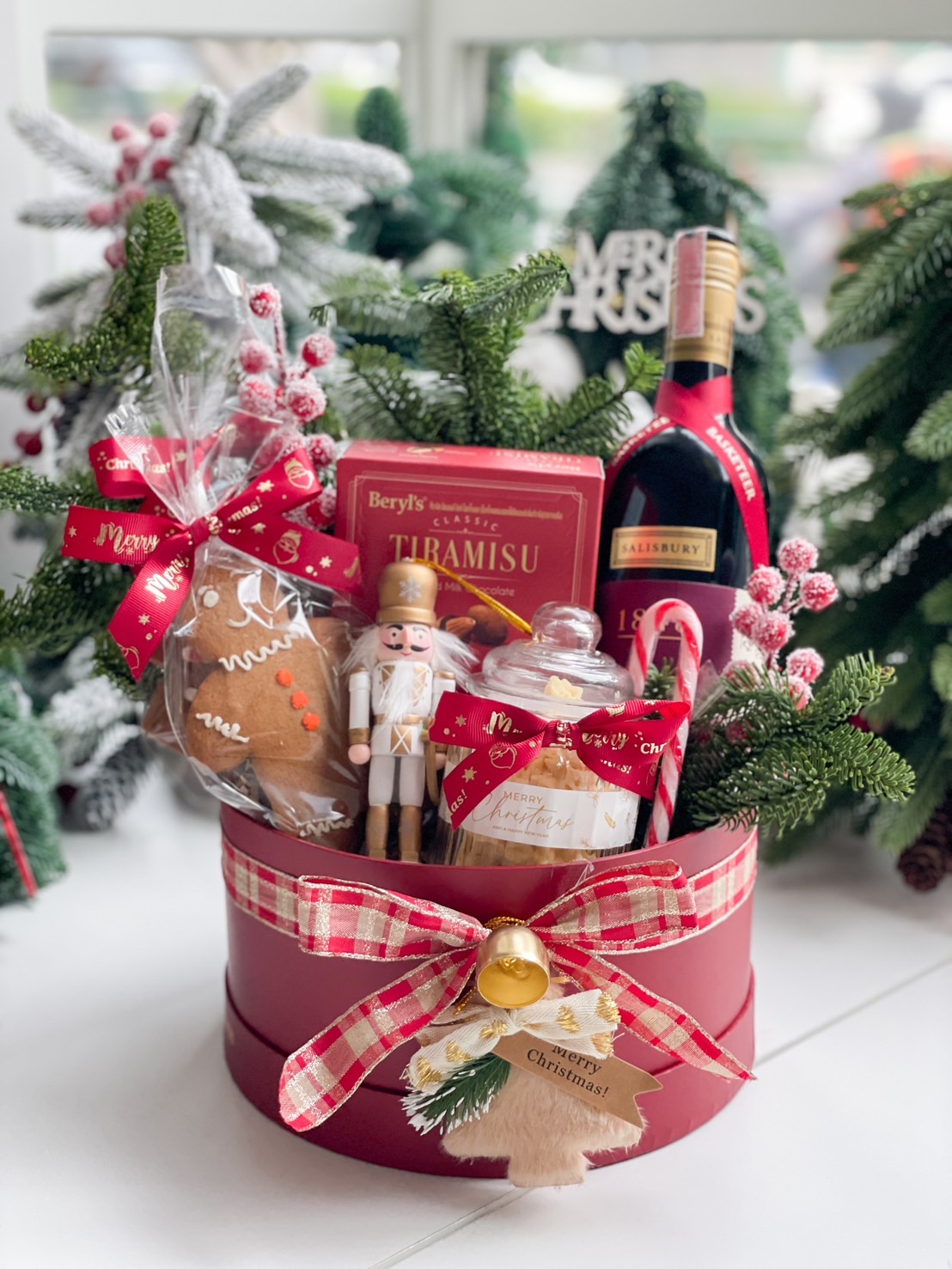 Red velvet gift box featuring 1848 wine, Tiramisu chocolates, a gingerbread cookie, and holiday-inspired cookies with festive decorations.