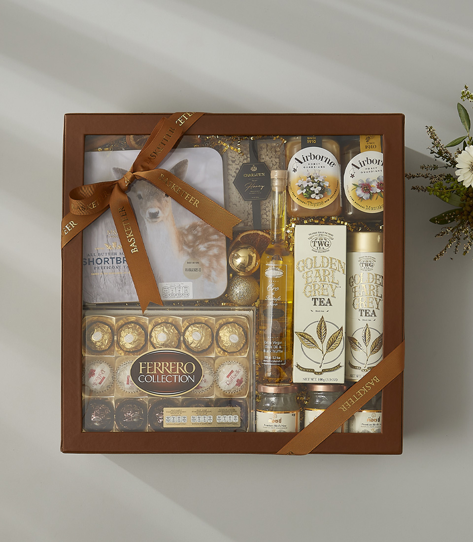 Elegant gift hamper featuring Ferrero chocolates, TWG Golden Earl Grey tea, gourmet honey, shortbread cookies, and luxury holiday treats.