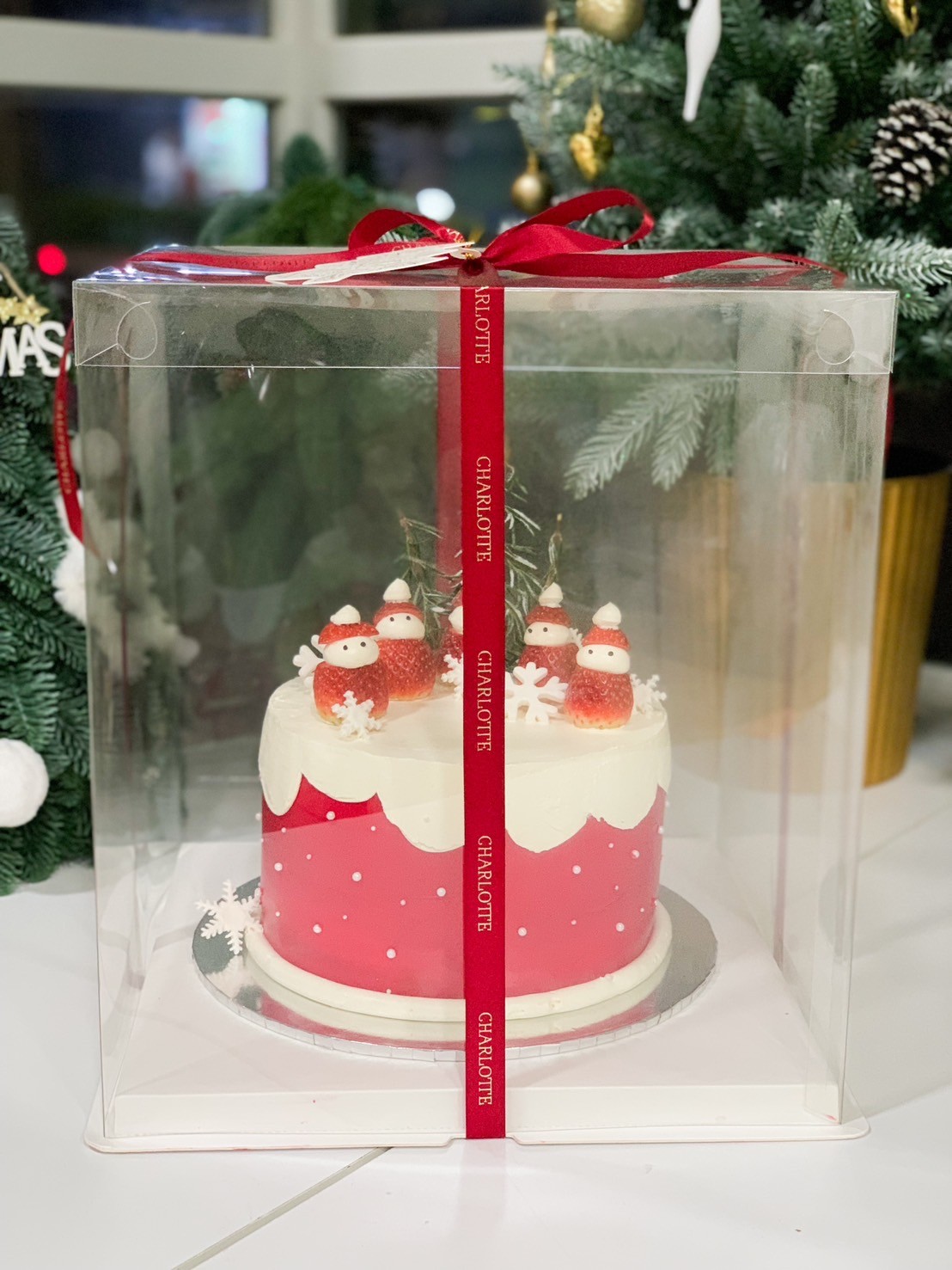 Christmas snowman strawberry cake in a transparent gift box adorned with red ribbons, perfect for festive celebrations.