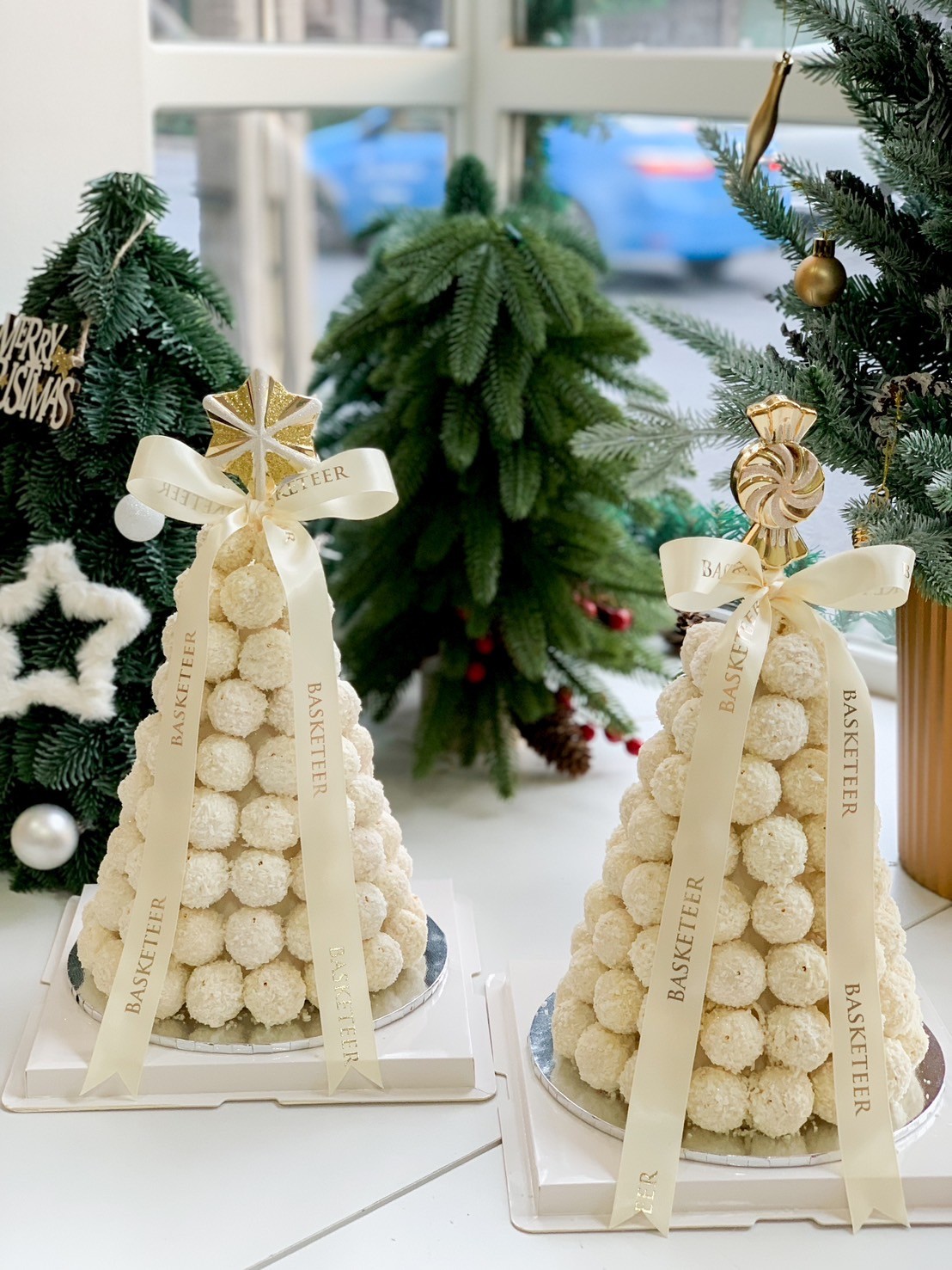 Two elegant white chocolate coconut towers wrapped in Basketeer ribbons, ideal for festive gifting or table decor.