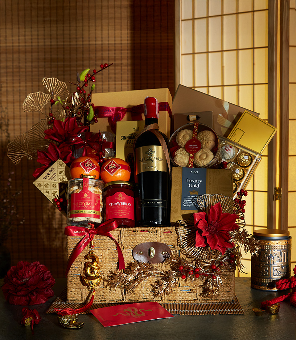 Elegant Chinese New Year gift basket with premium wine, cookies, oranges, and luxurious red and gold decorations.