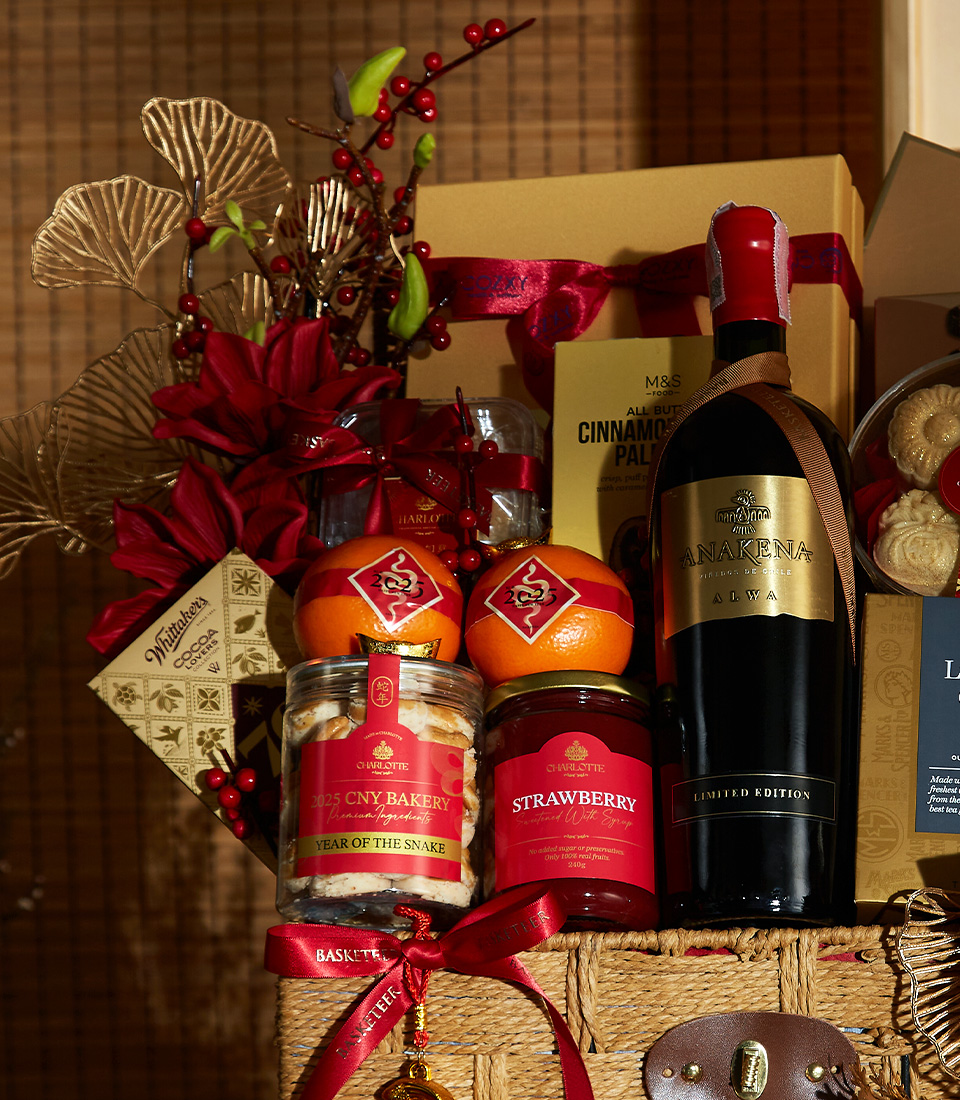 Close-up of a Elegant Chinese New Year gift basket with premium wine, cookies, oranges, and luxurious red and gold decorations.