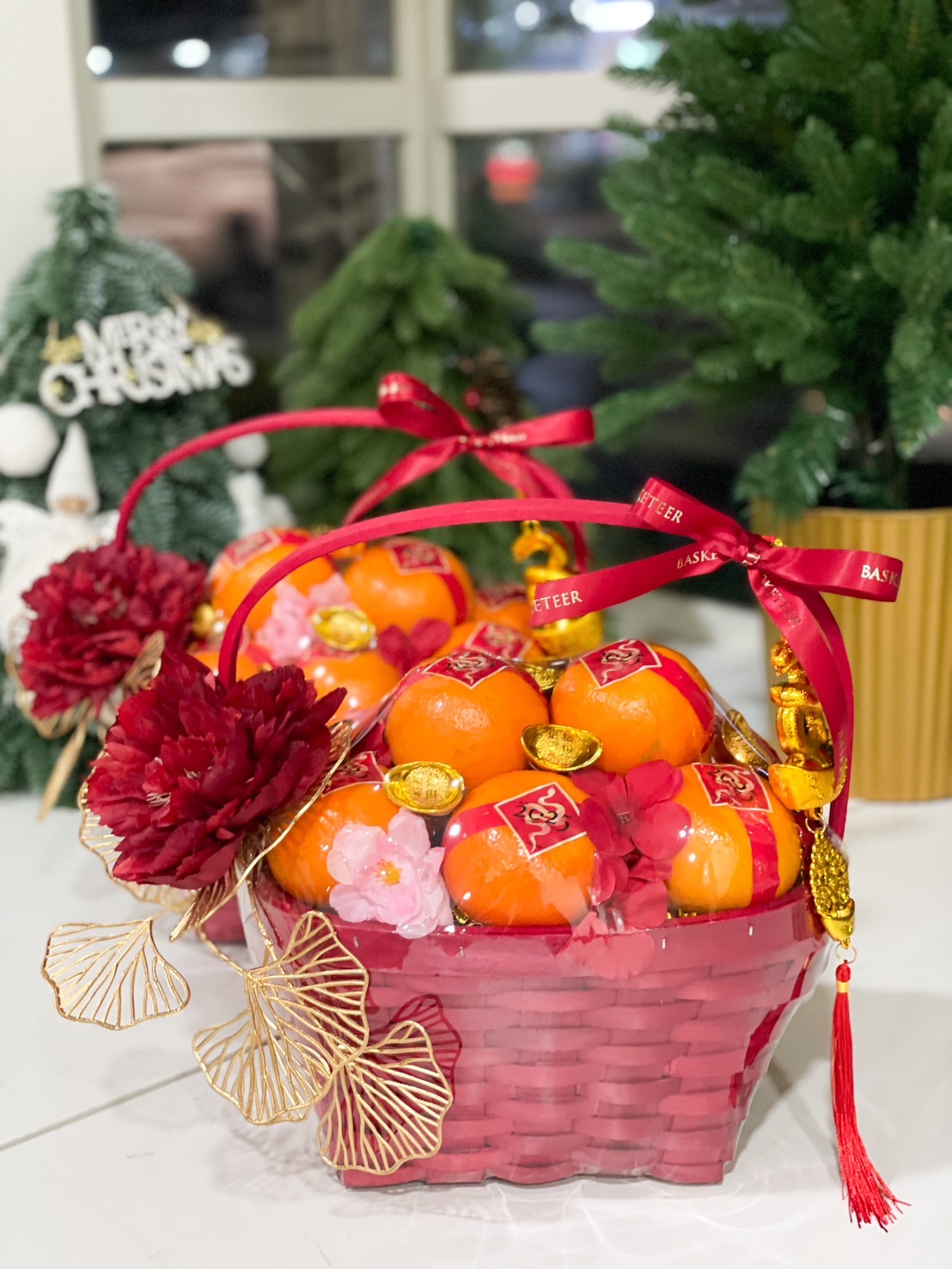 Two Chinese New Year gift basket with fresh mandarins, golden ingots, red and gold decorations, and a festive ribbon for celebrations.