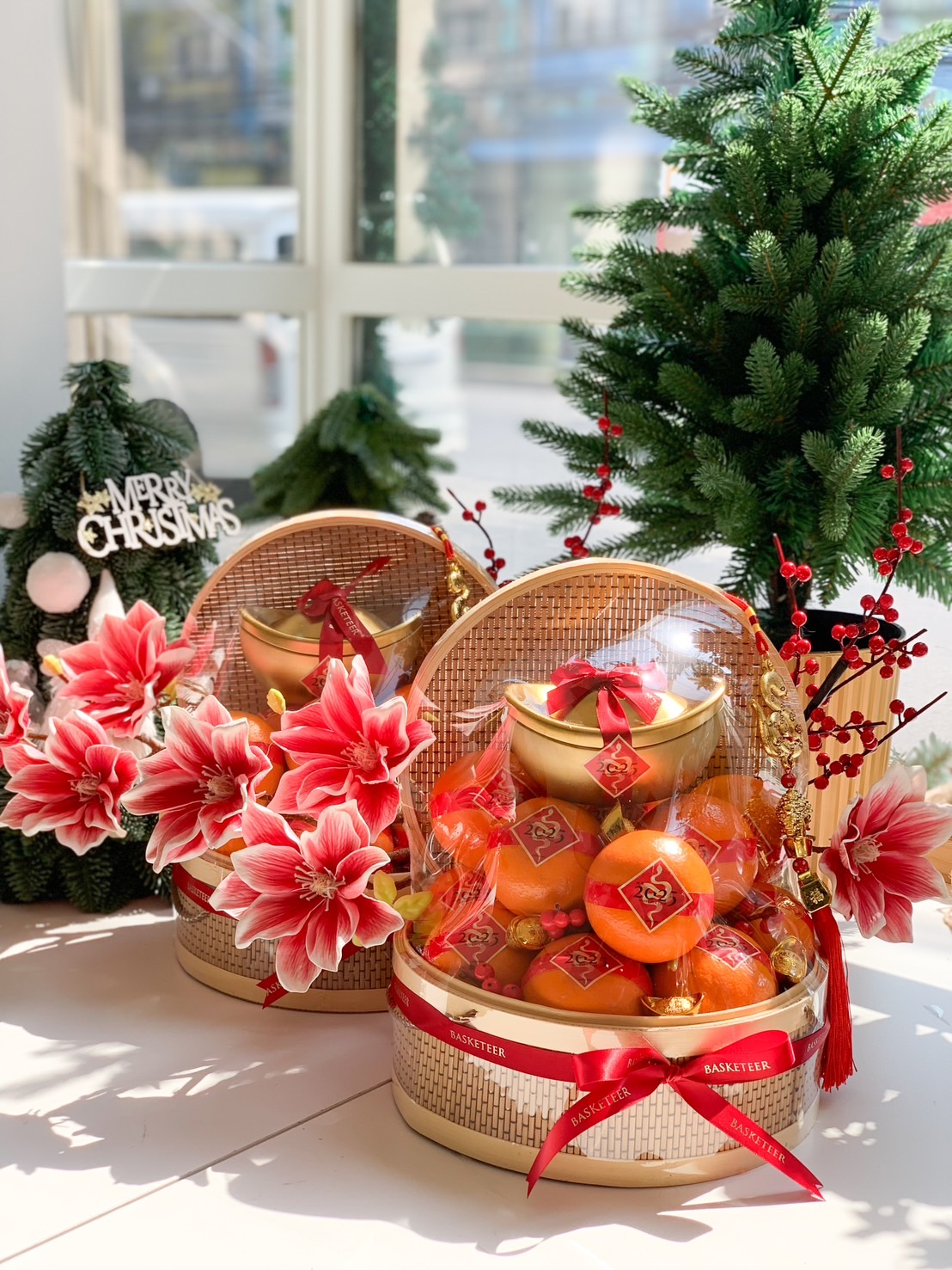 Elegant Chinese New Year basket with fresh mandarins, a gold ingot centerpiece, and adorned with red and gold flowers, wrapped in clear protective cover.