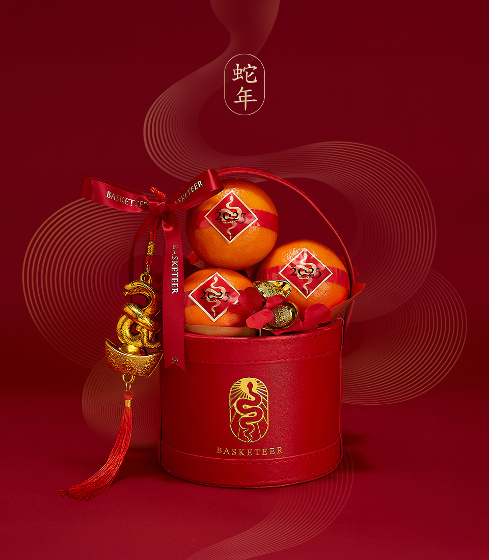 Red gift box featuring fresh mandarin oranges with gold accents and festive Chinese New Year decorations for the Year of the Snake.