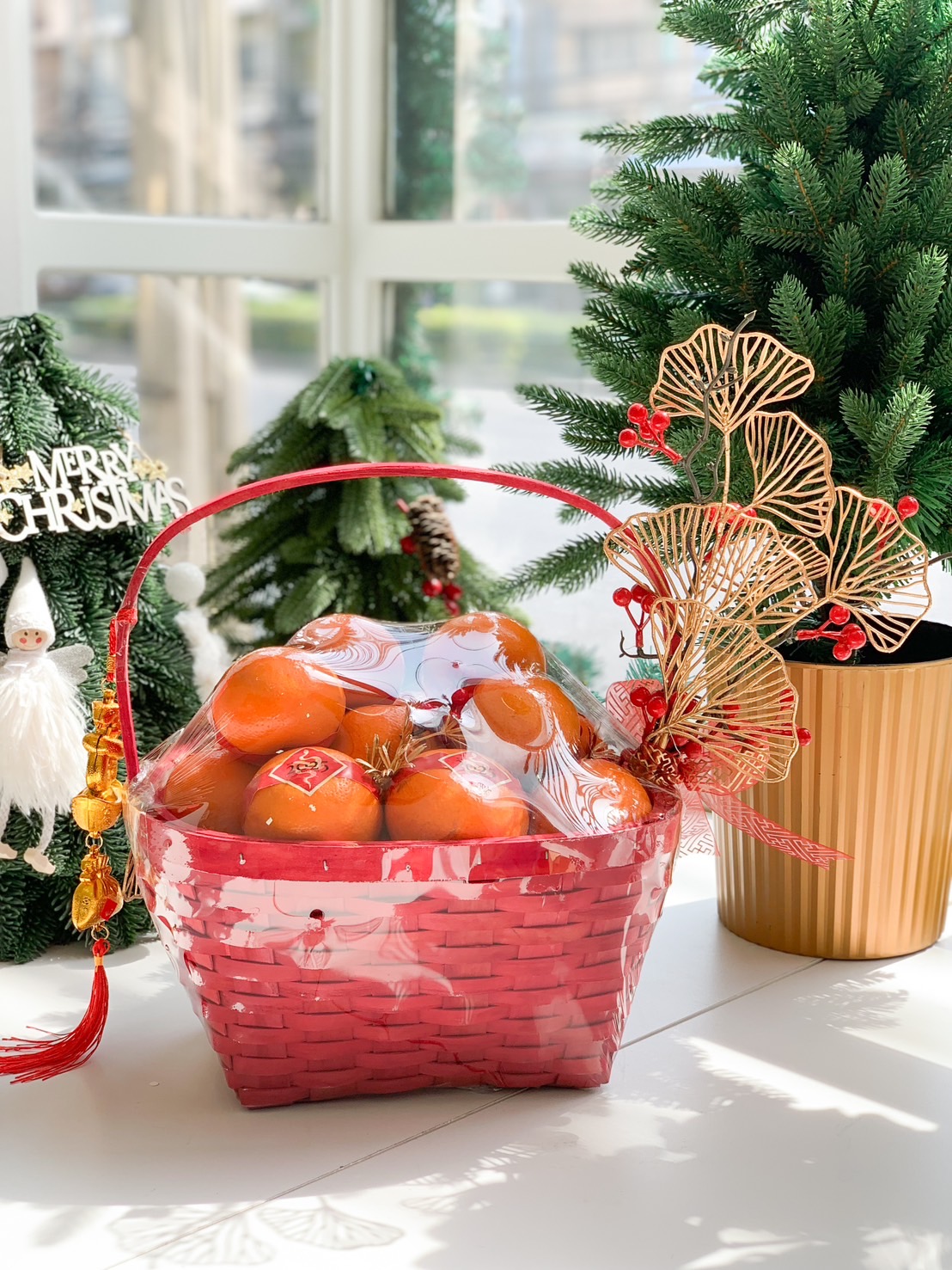 Red Chinese New Year gift basket filled with fresh mandarins, adorned with gold decorations and vibrant red festive accents.