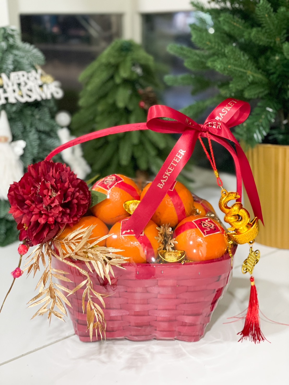 Chinese New Year gift basket with fresh mandarins, golden ingots, red and gold decorations, and a festive ribbon for celebrations.