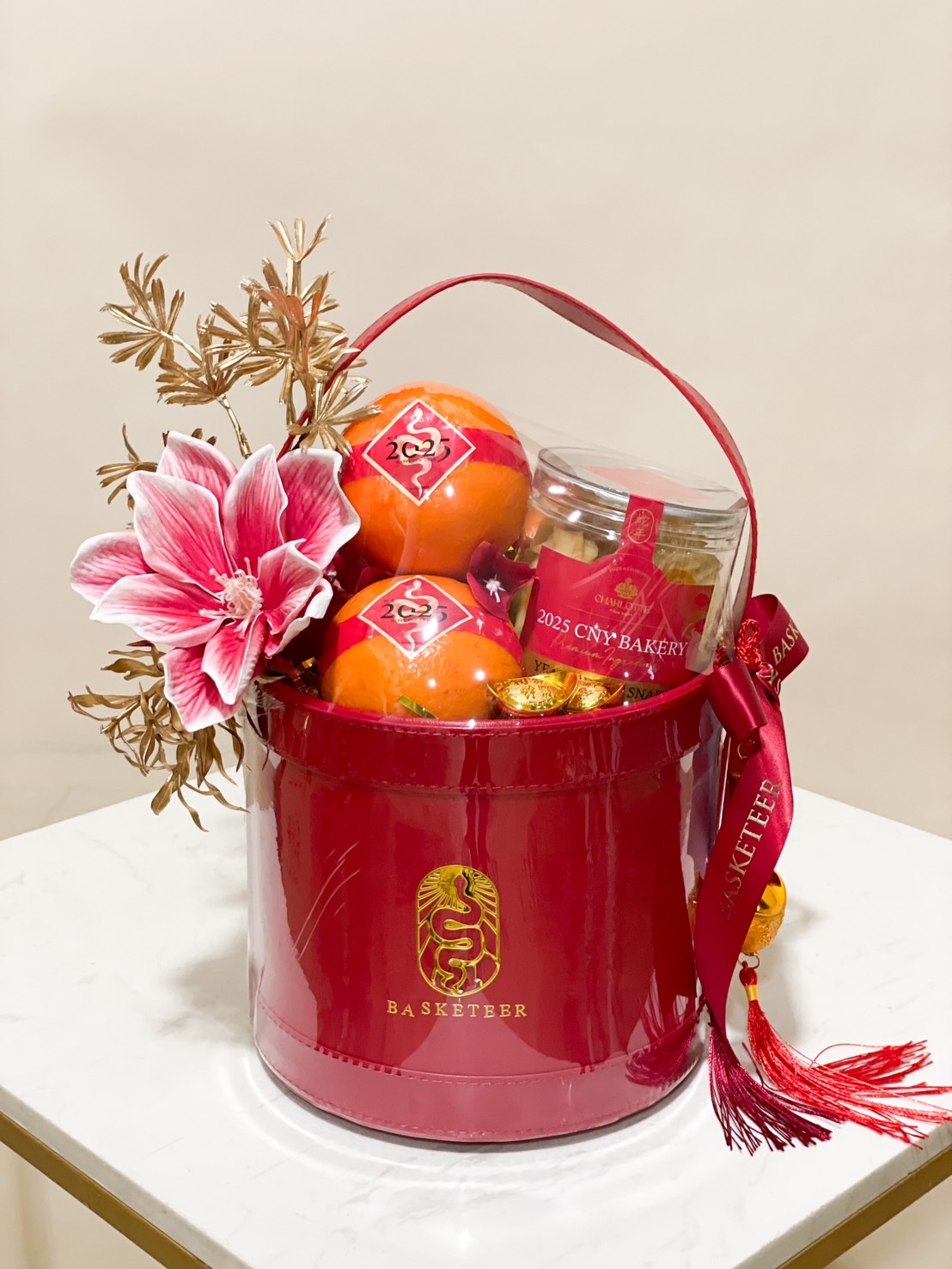 Chinese New Year red basket with premium oranges, bakery treats, and festive decorations.