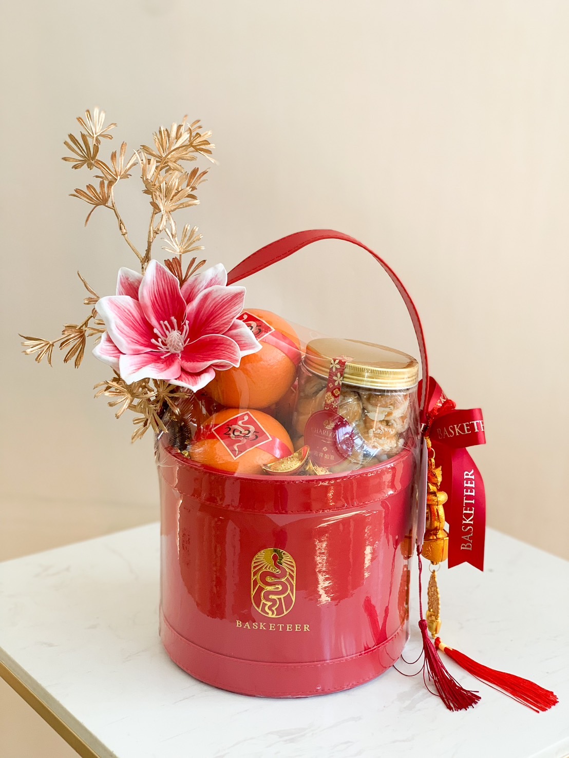Chinese New Year red basket with premium oranges, bakery treats, and festive decorations.
