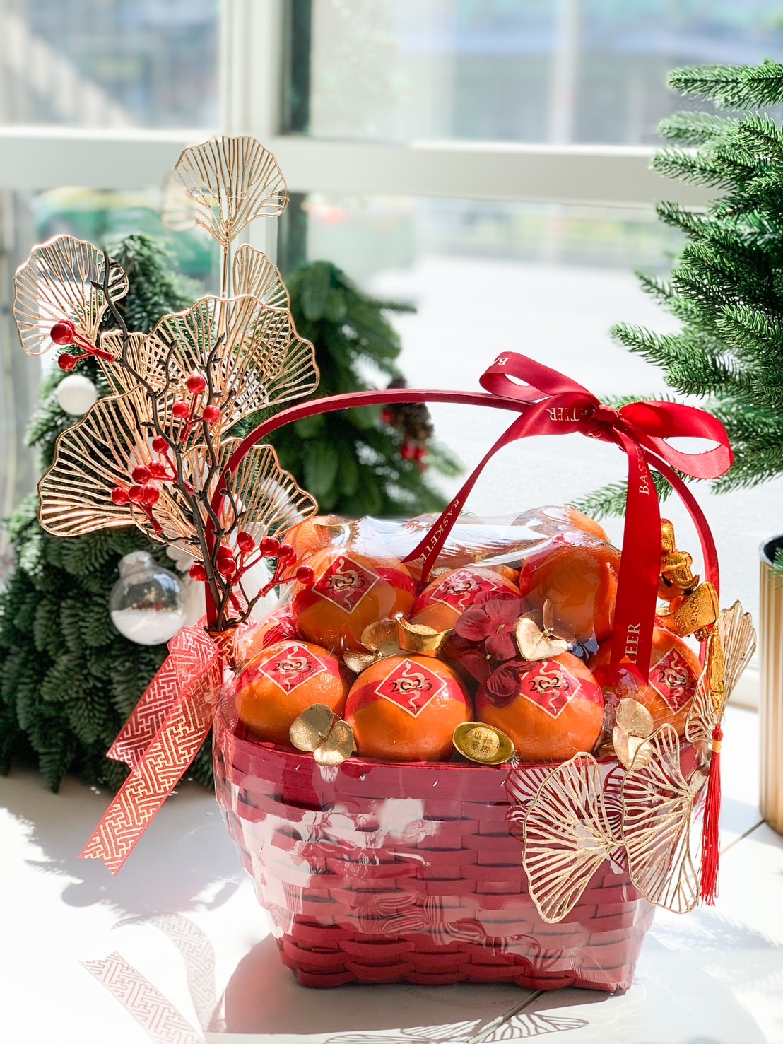Red Chinese New Year gift basket filled with fresh mandarins, adorned with gold decorations and vibrant red festive accents.