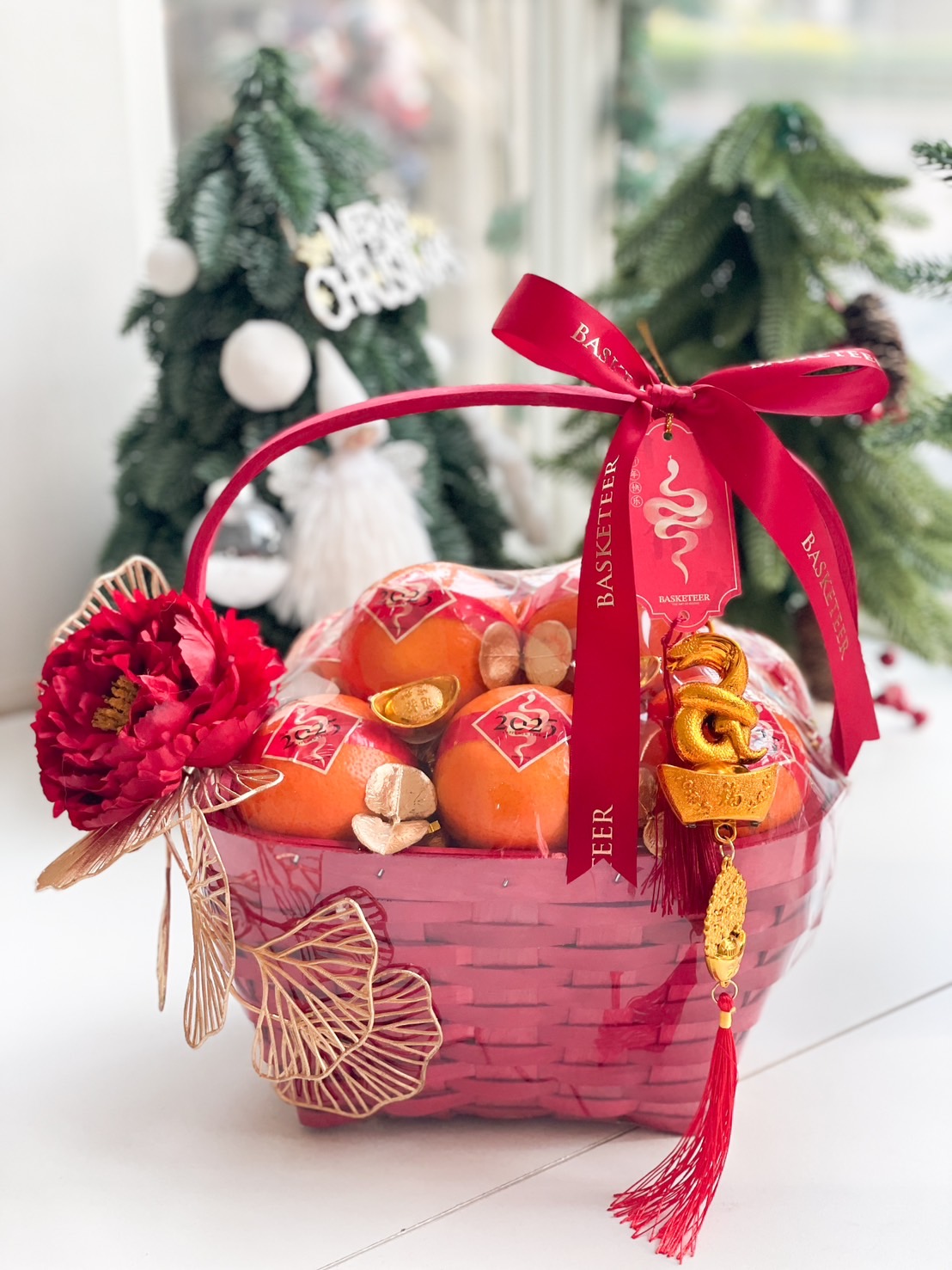 Red Chinese New Year gift basket featuring fresh oranges, gold decorations, red ribbons, and a festive charm.