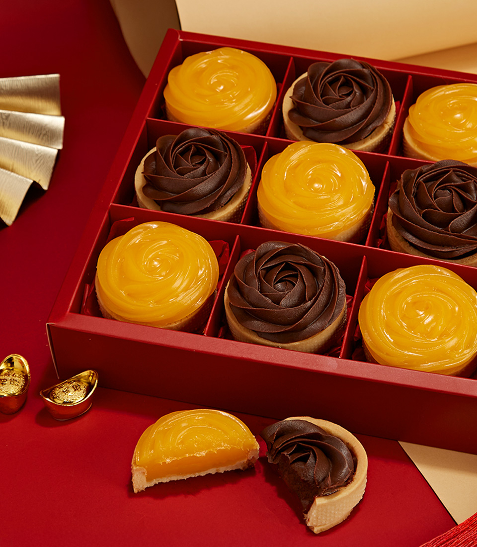 Close-up of a golden citrus and chocolate tarts in a red gift box, designed for festive gifting and celebrations.