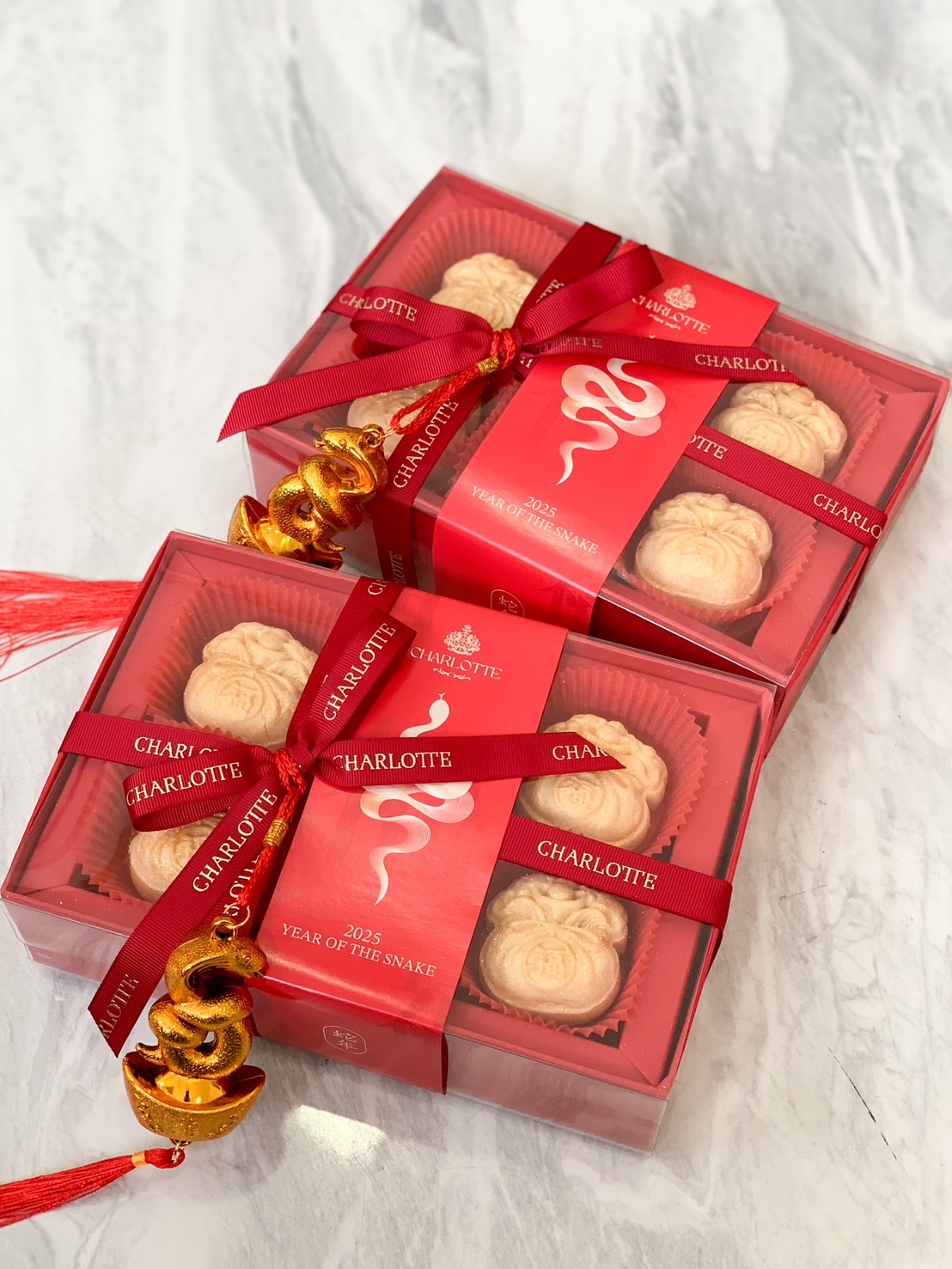 Chinese New Year fortune Pineapple Cakes in red gift boxes with golden snake charms and festive ribbons.