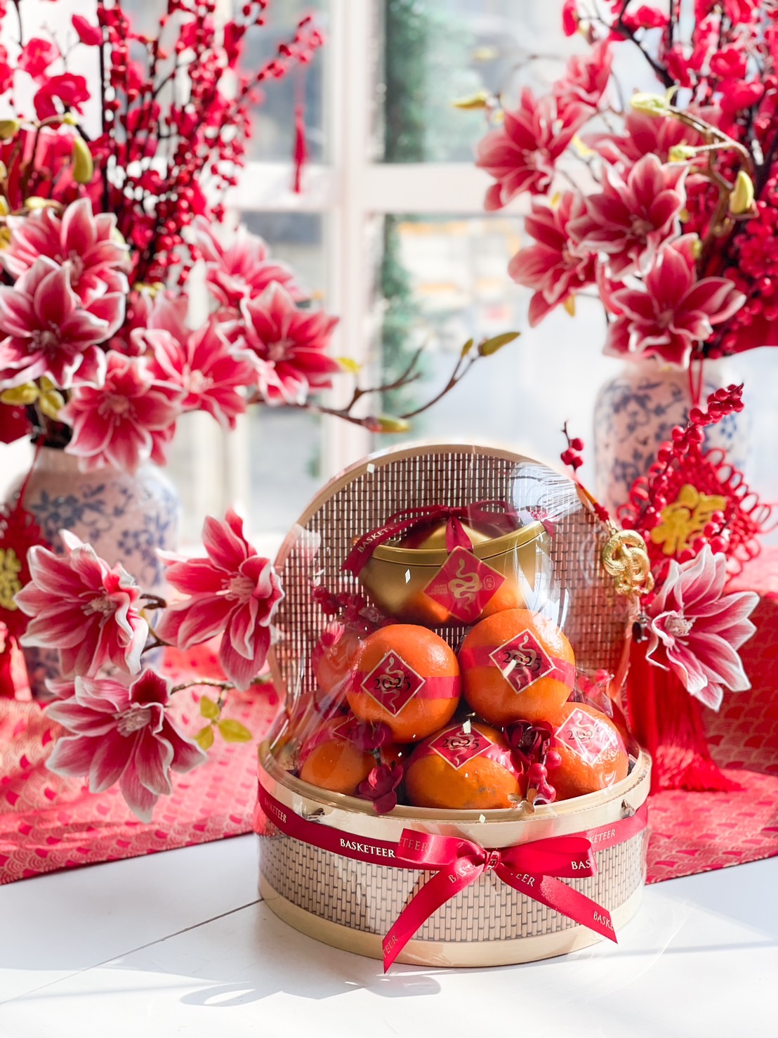 A beautifully arranged Chinese New Year gift basket filled with fresh mandarin oranges, adorned with festive red ribbons and gold decorations.