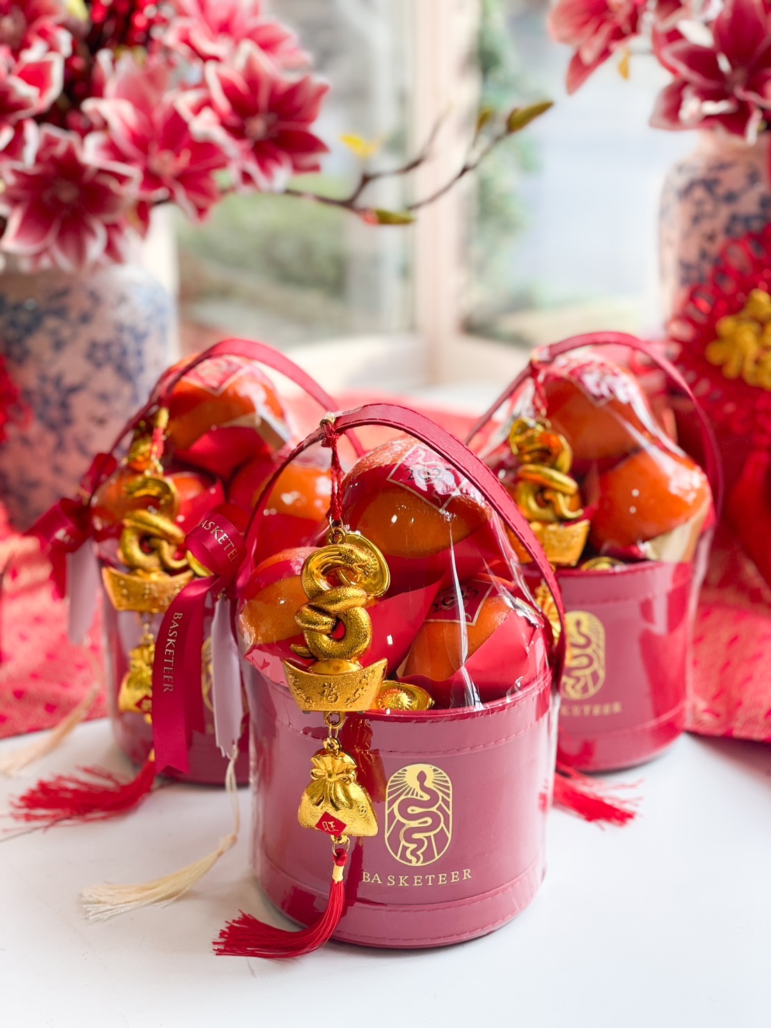 Luxury Chinese New Year prosperity gift basket with Mandarin oranges, gold charms, and red festive packaging for a celebration of wealth and good fortune.