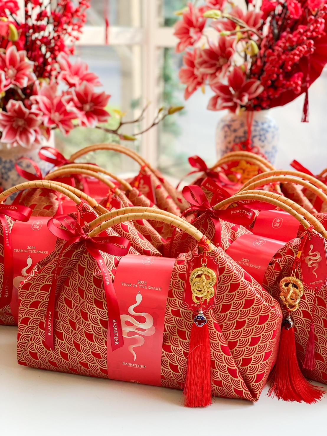 Chinese New Year luxury fortune gift bag wrapped in red fabric with gold patterns, a bamboo handle, and festive prosperity charms.
