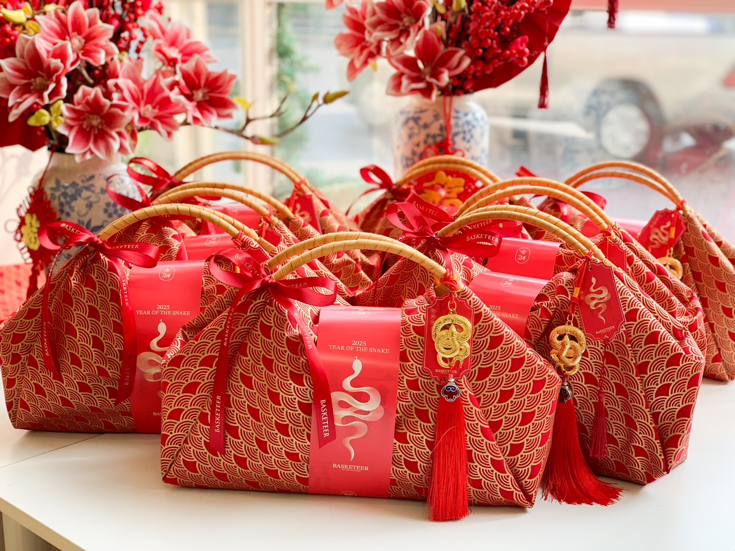 Chinese New Year luxury fortune gift bag wrapped in red fabric with gold patterns, a bamboo handle, and festive prosperity charms.
