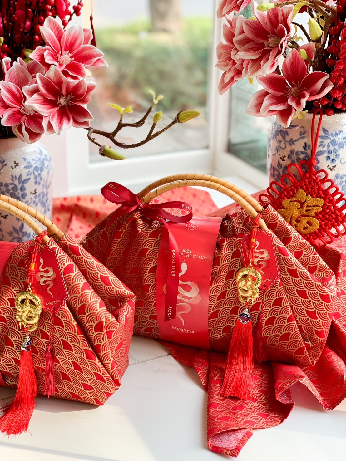 Luxury Chinese New Year fabric hamper set with red and gold fabric wrapping, bamboo handles, and prosperity charms for an elegant festive gift.