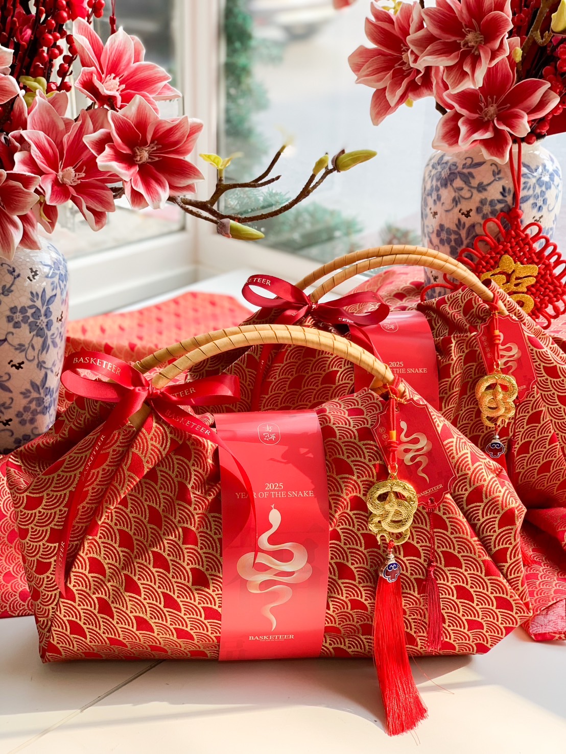 Luxury Chinese New Year fabric hamper set with red and gold fabric wrapping, bamboo handles, and prosperity charms for an elegant festive gift.