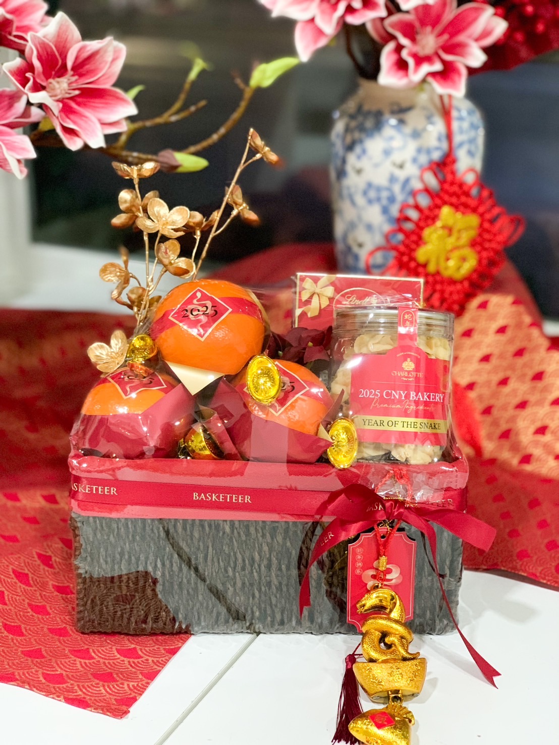 Chinese New Year deluxe gift basket with Mandarin oranges, festive treats, gold ingots, and elegant red packaging for prosperity and luck.