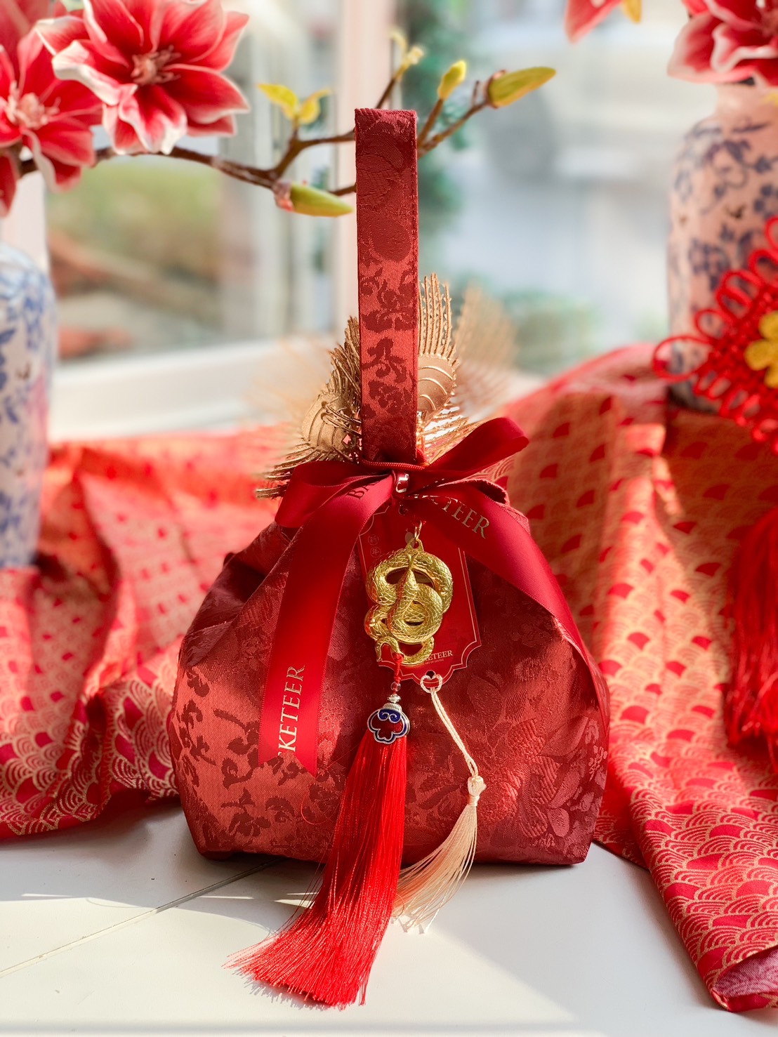 Luxury Chinese New Year fortune gift bag with red brocade fabric, gold accents, festive ribbon, and a lucky charm for prosperity.