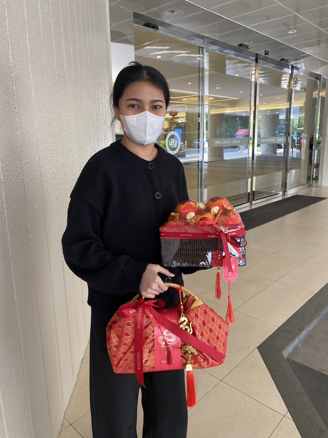 Chinese New Year gift set with a woven fortune basket of mandarin oranges and a red fabric-wrapped prosperity bundle with a bamboo handle.