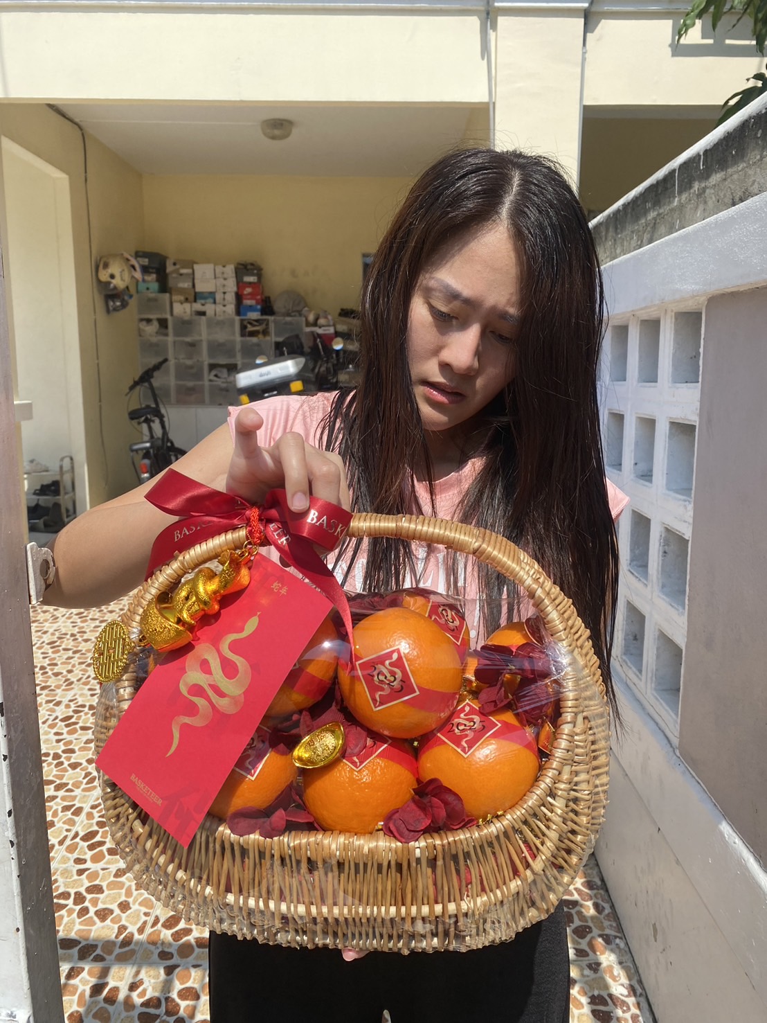 Mini Chinese New Year gift baskets with mandarin oranges, festive treats, red floral decorations, and gold accents for good fortune.