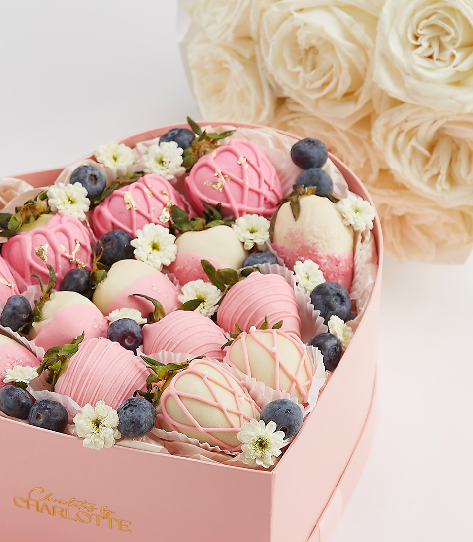Close-up of a luxury heart-shaped gift box with chocolate-covered strawberries, blueberries, and fresh flowers for an elegant and romantic presentation.
