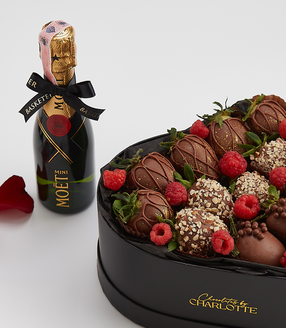 Heart-shaped gift box with dark chocolate-covered strawberries, fresh raspberries, nuts, and a bottle of Moët & Chandon champagne.