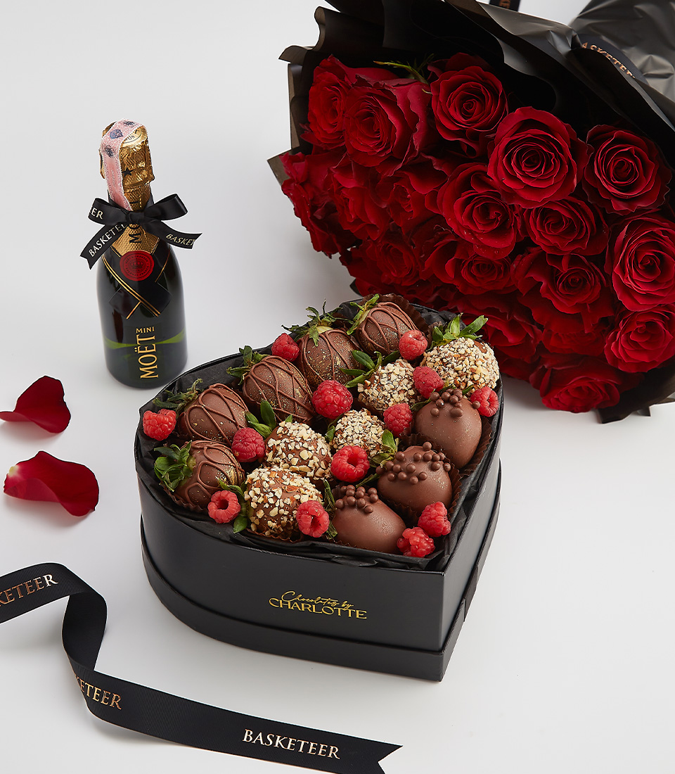 Luxury heart-shaped chocolate strawberry gift box with Moët champagne and a bouquet of red roses.