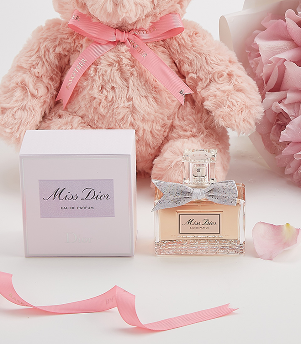 Close-up of a luxurious Valentine’s gift set including a plush pink teddy bear, elegant pink roses, and Miss Dior perfume, beautifully arranged for a heartfelt surprise.