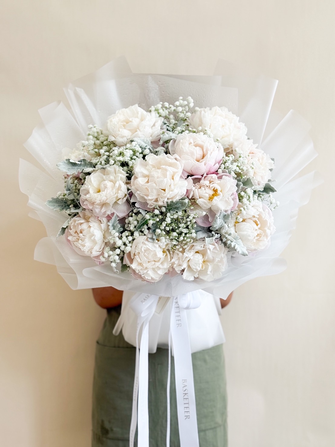 Large white peony bouquet with baby’s breath and dusty miller, wrapped in sheer white paper