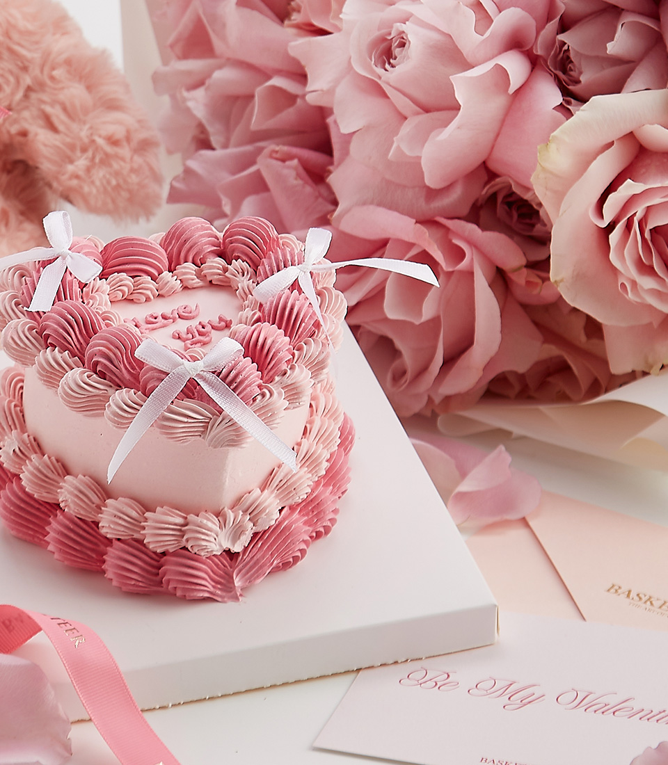 Close-up of a soft pink rose bouquet, heart-shaped cake, and plush teddy bear—a luxurious Valentine’s gift set designed for romance.