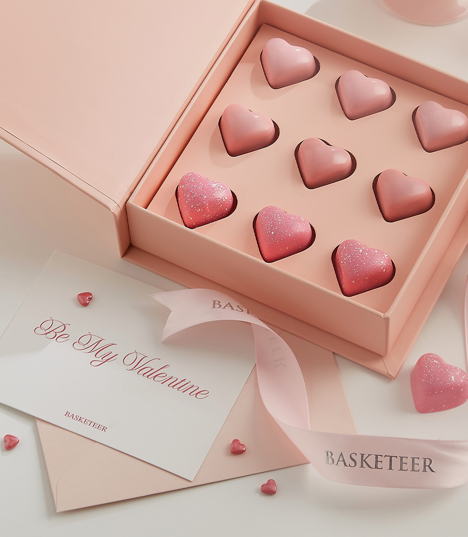 Close-up of a luxury pink box filled with heart-shaped chocolates, featuring smooth pink coatings and a touch of shimmer, perfect for Valentine’s gifting.