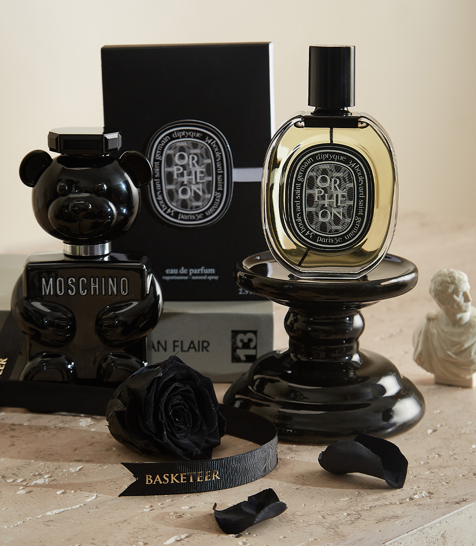 Close-up of a luxurious gift set featuring a black preserved rose under a glass dome, designer fragrances, handcrafted chocolates, and an elegant black candle—ideal for a stylish and meaningful gift.