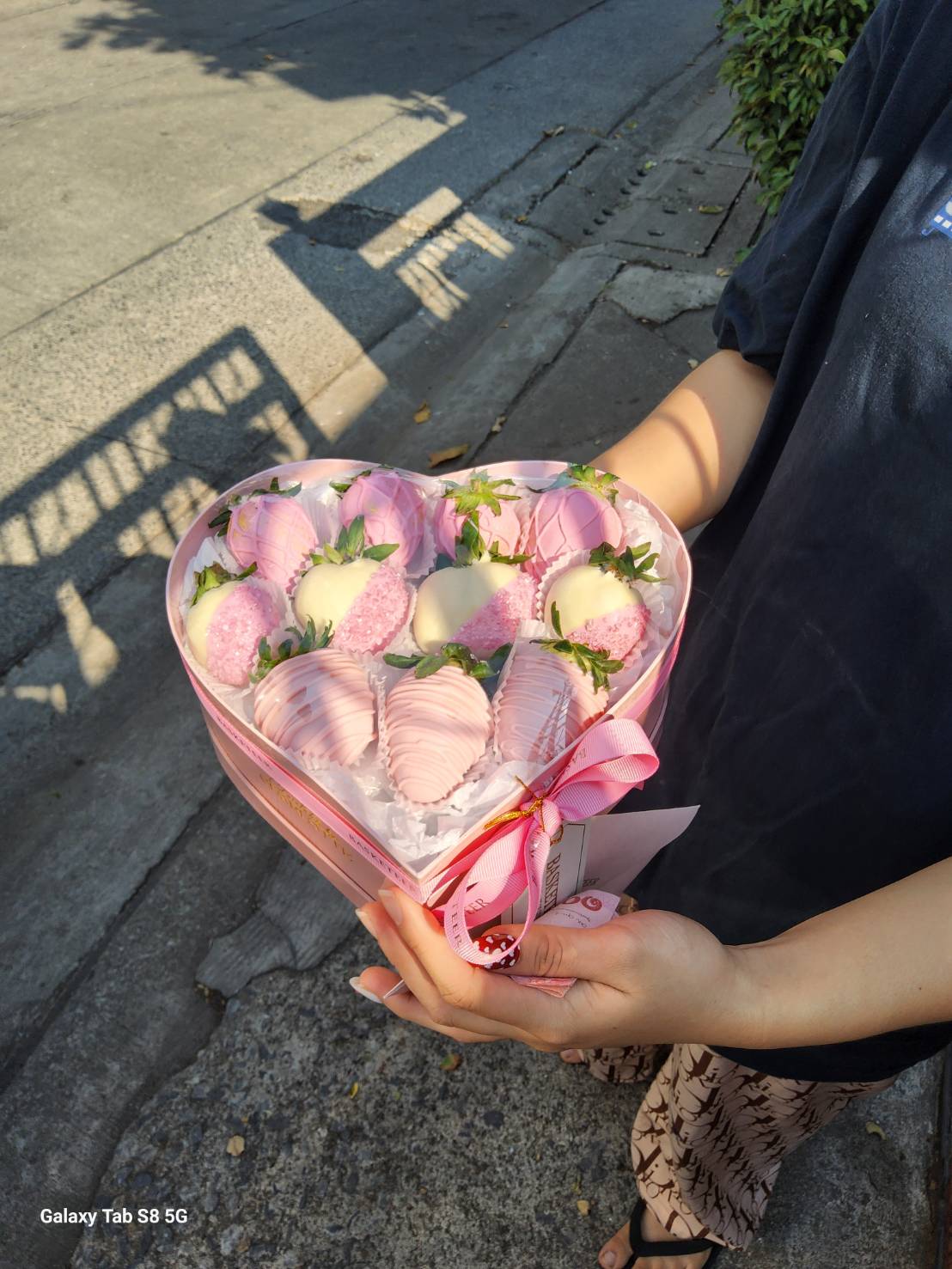 Heart-shaped box filled with pink and white chocolate-covered strawberries, decorated beautifully for a luxury gift.