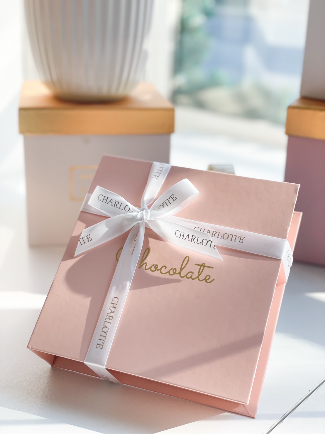 A luxurious pink chocolate gift box with a satin ribbon, perfect for gifting on special occasions.