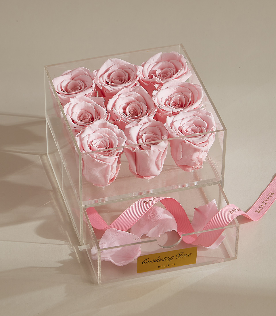 A stunning preserved pink rose arrangement featuring nine delicate roses in a clear acrylic box with a keepsake drawer, finished with a pink ribbon.