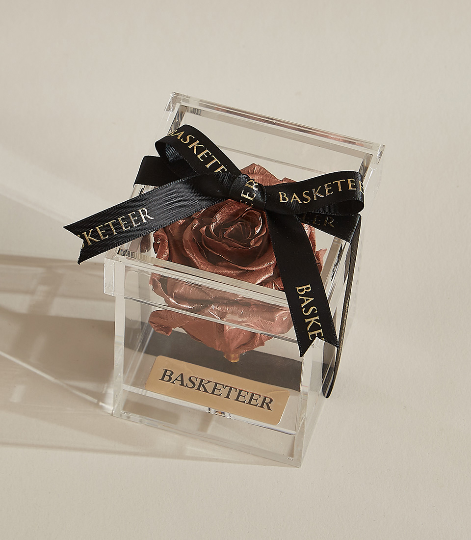 A single bronze preserved rose beautifully presented in a transparent acrylic box with a gold-engraved Basketeer nameplate.