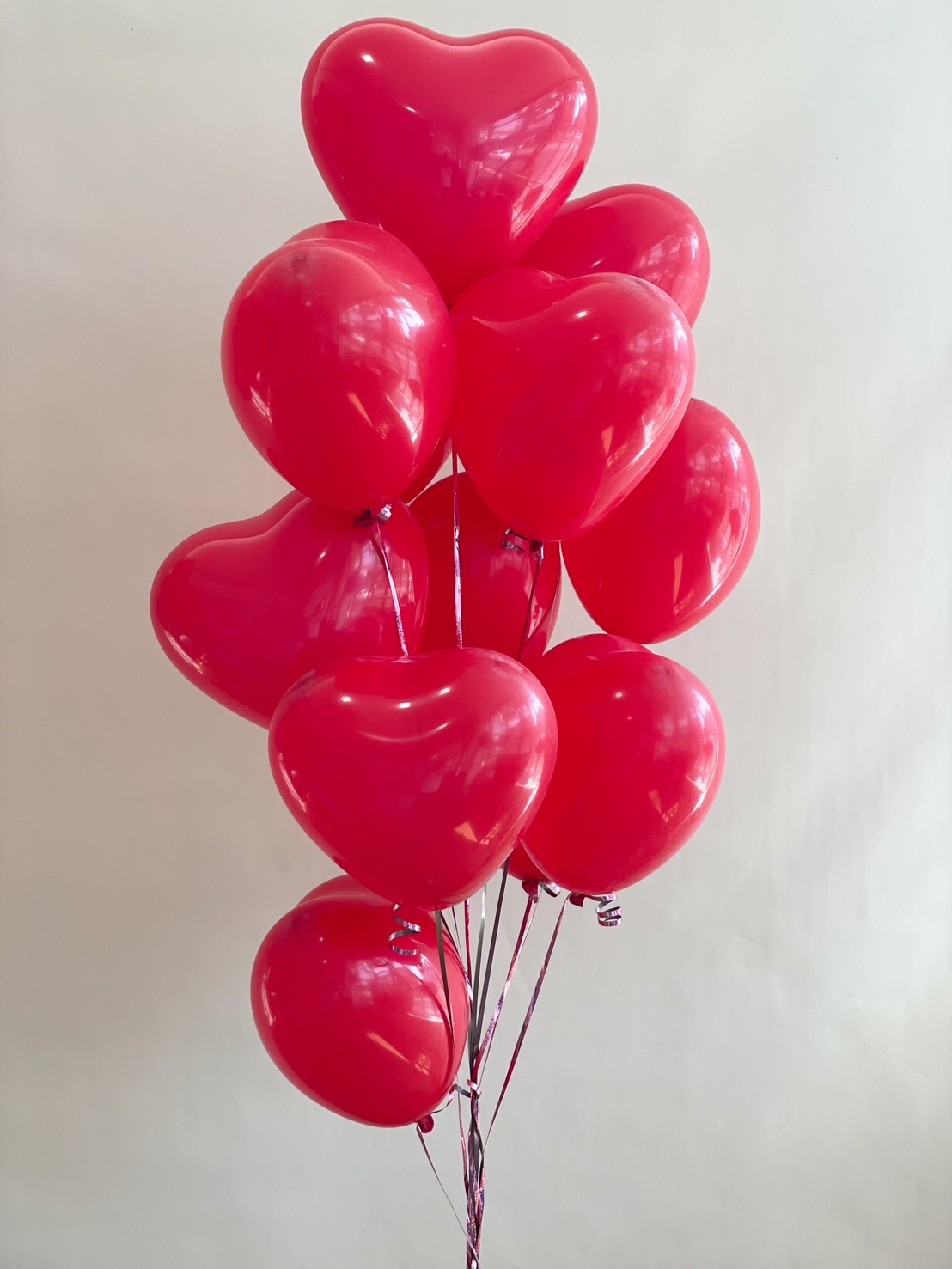 A bouquet of 10 helium-filled red heart-shaped balloons, perfect for romantic celebrations, Valentine's Day, and anniversaries.