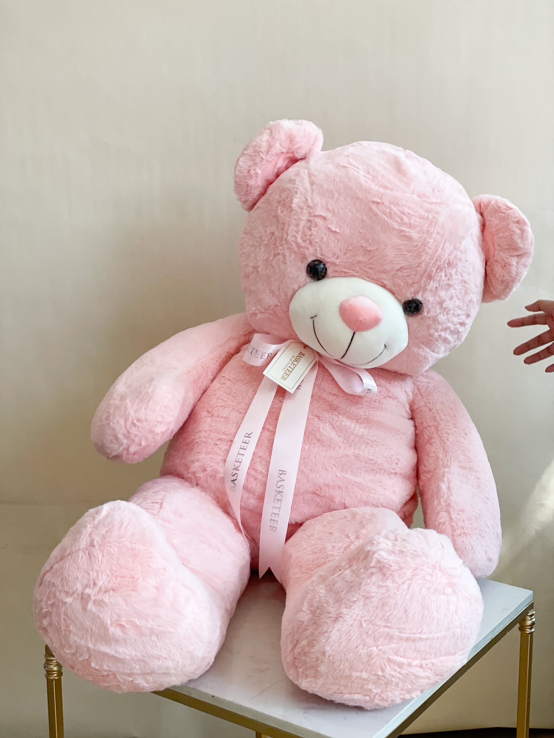 A giant pink plush teddy bear with a Basketeer ribbon and tag, perfect for Valentine’s gifts, birthdays, and romantic surprises.