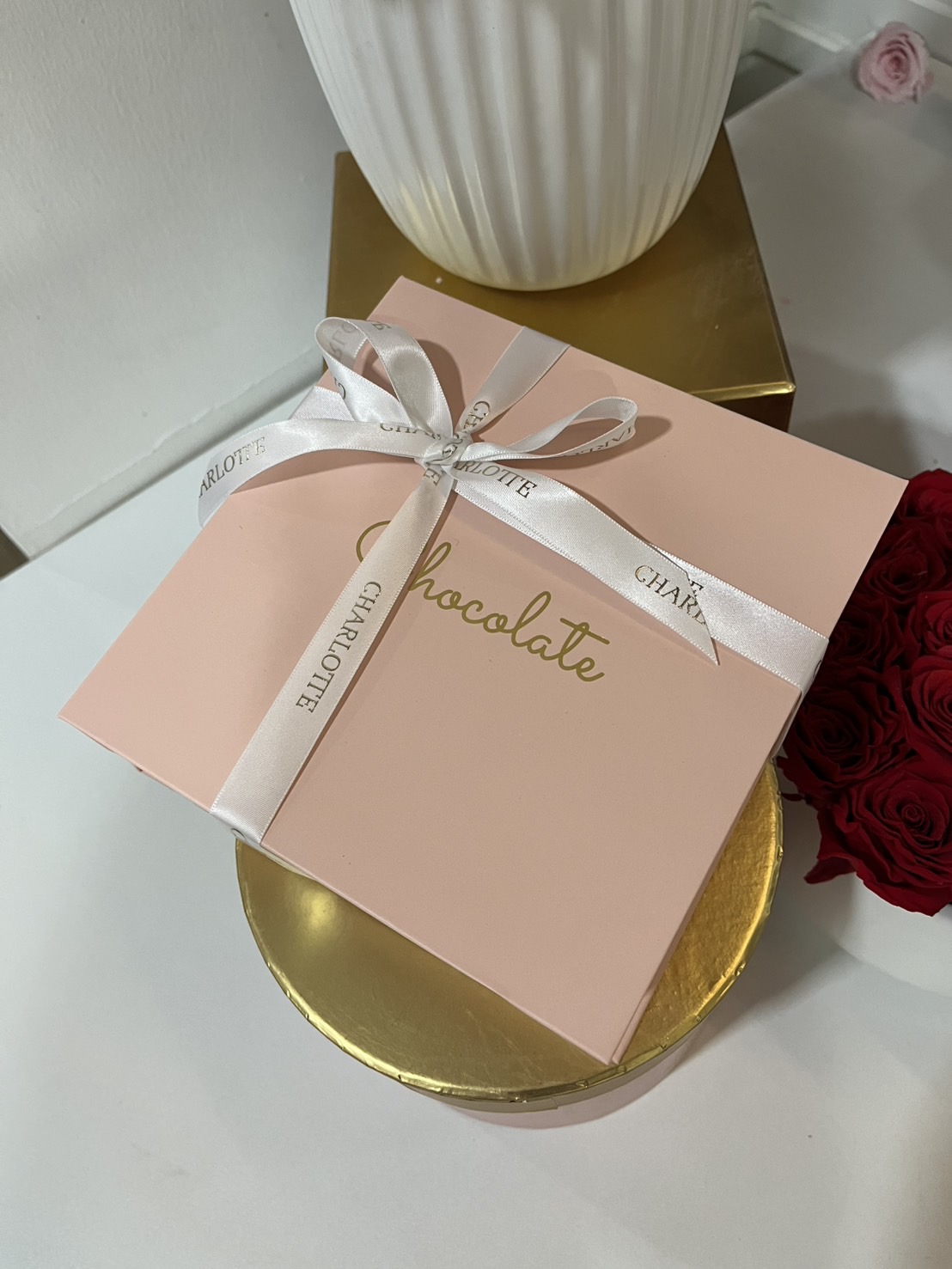 A luxurious pink chocolate gift box with a satin ribbon, perfect for gifting on special occasions.