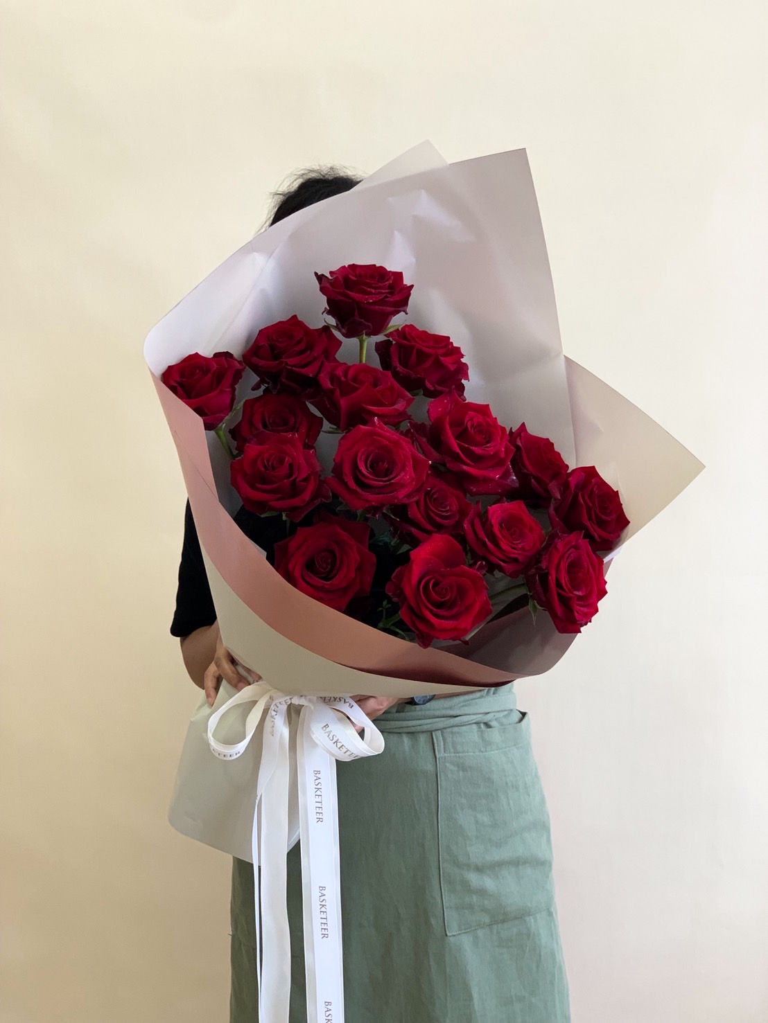 Elegant bouquet of 15 red roses wrapped in matte white and blush pink paper with a white Basketeer ribbon.