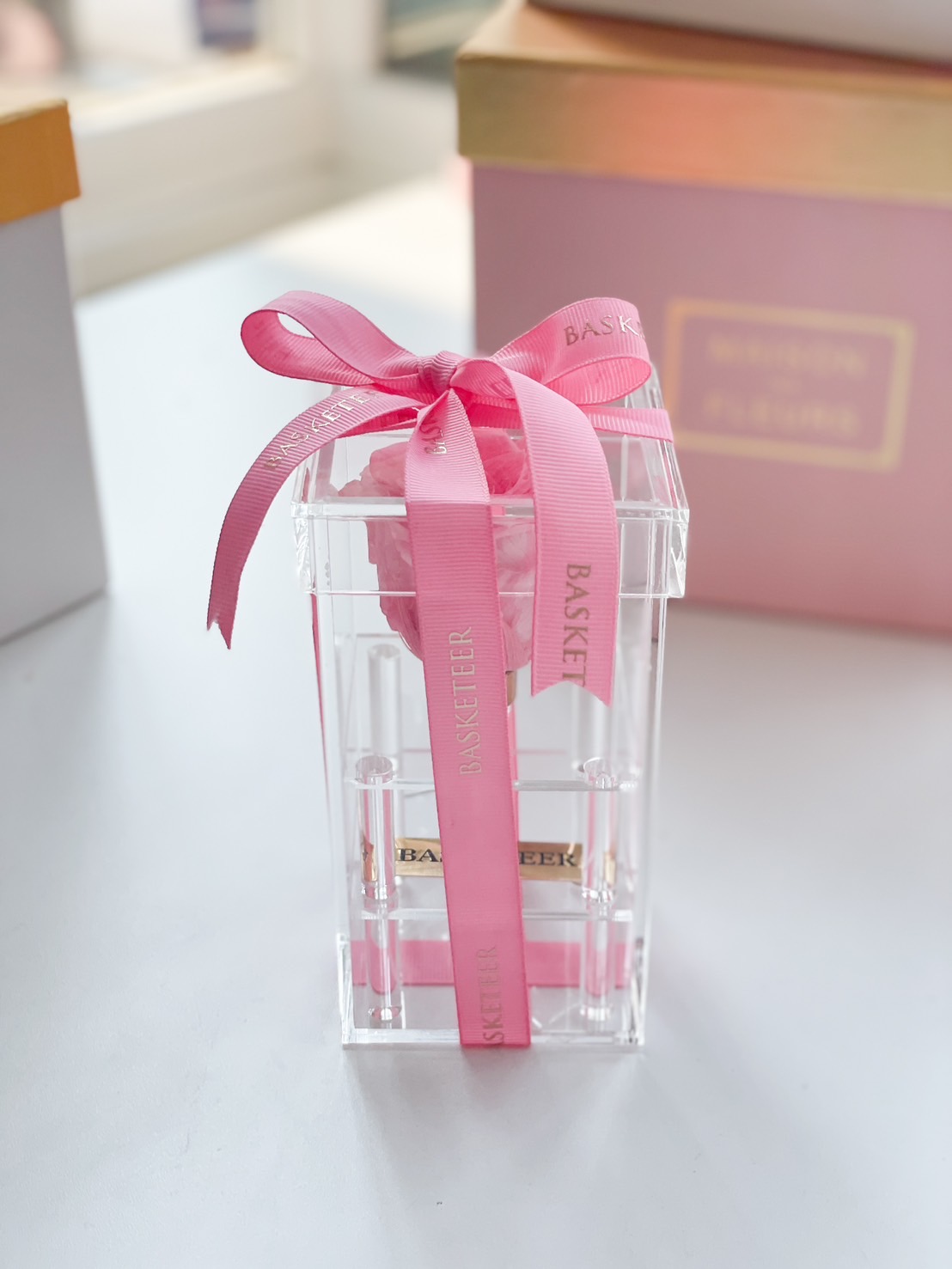Elegant pink preserved rose in a clear acrylic box, wrapped with a luxury pink ribbon—a symbol of eternal love.