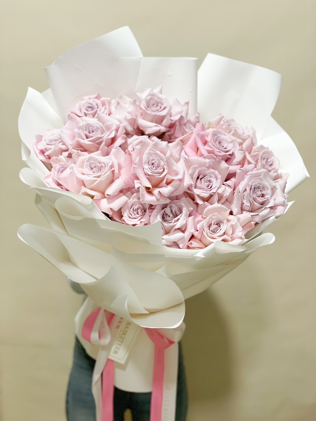 A luxurious bouquet of soft pink roses, wrapped in white with a pink satin ribbon, ideal for romantic gifts and special occasions.