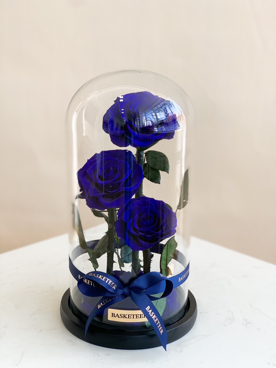 A stunning preserved blue rose arrangement enclosed in a luxury glass dome, elegantly tied with a navy blue ribbon. A timeless gift symbolizing eternal love and admiration. Perfect for anniversaries, birthdays, and special occasions.